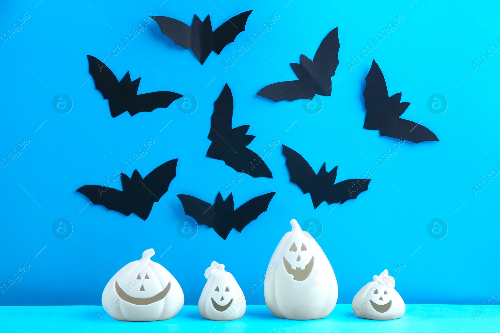 Photo of Composition with pumpkin shaped candle holders on blue background. Halloween decoration