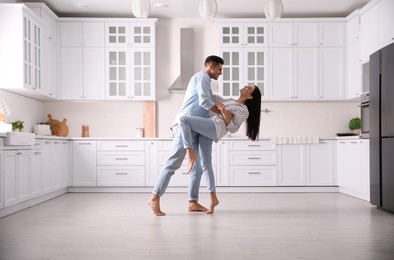 Happy couple dancing barefoot in kitchen. Floor heating system