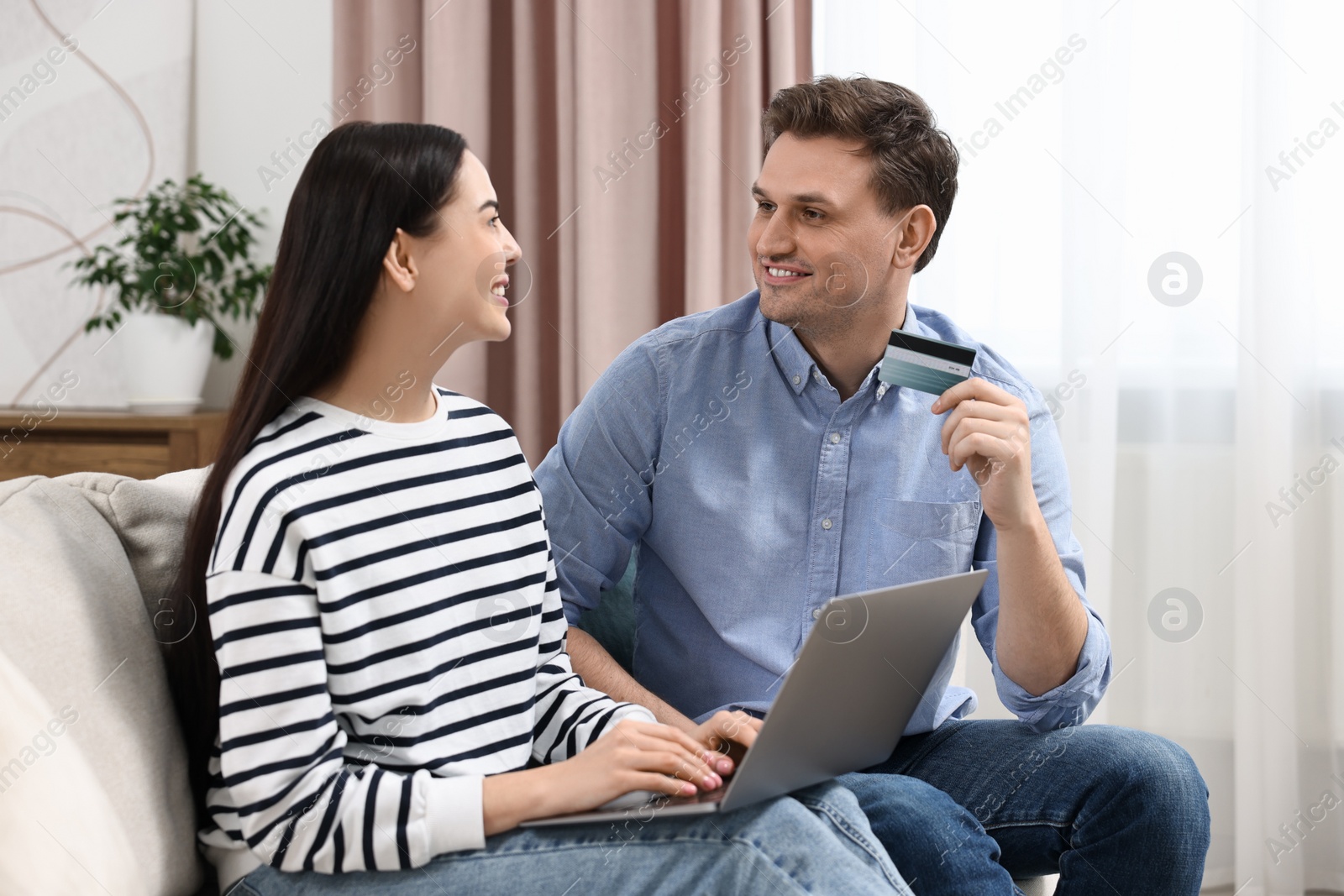 Photo of Happy couple with laptop and credit card shopping online together at home