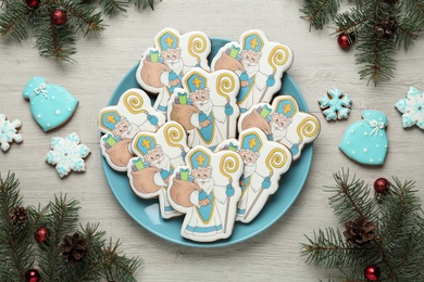 Photo of Flat lay composition with delicious gingerbread cookies on white wooden table. Happy St. Nicholas Day