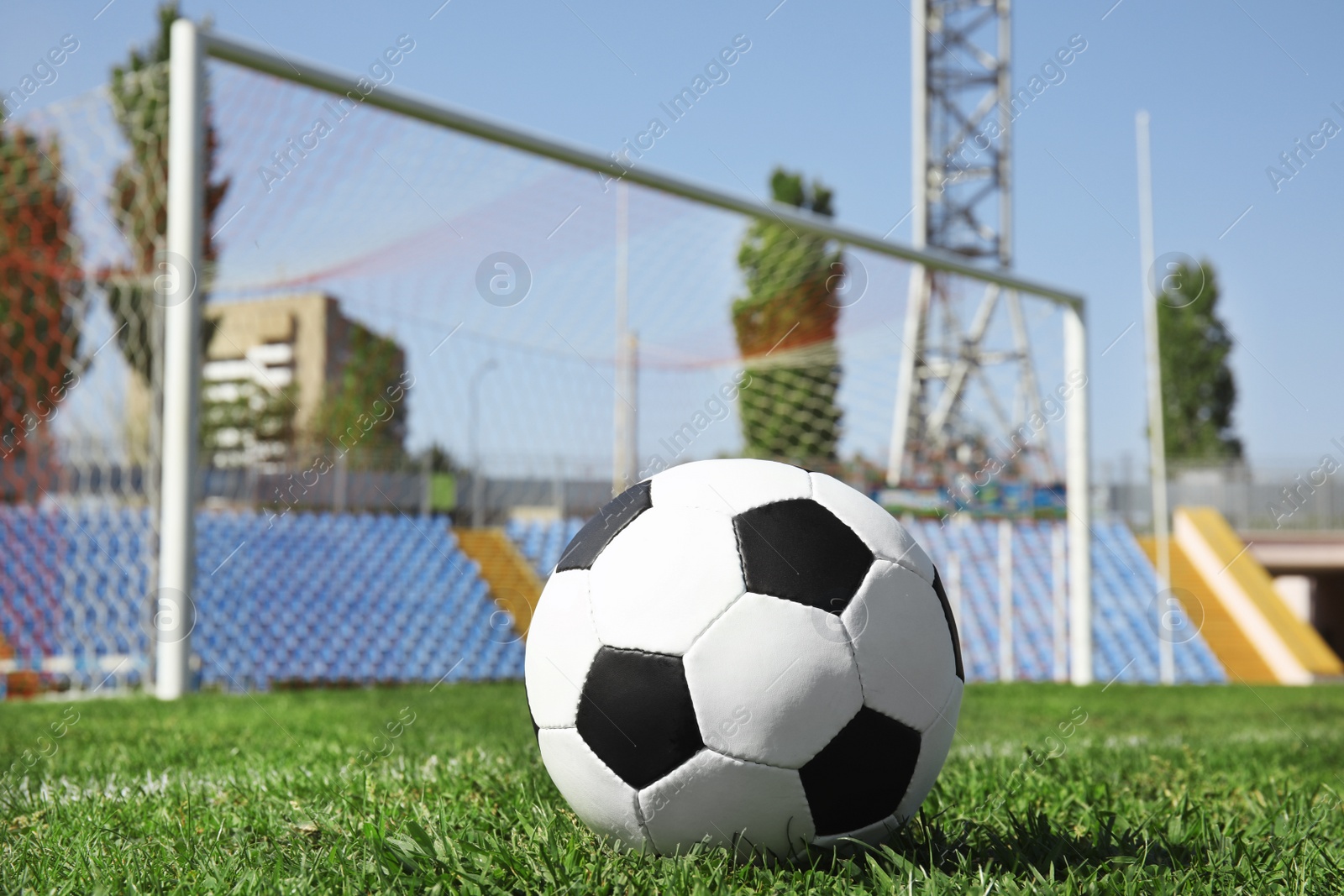 Photo of Soccer ball on green football field grass against net