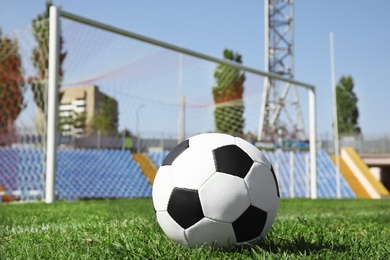 Photo of Soccer ball on green football field grass against net