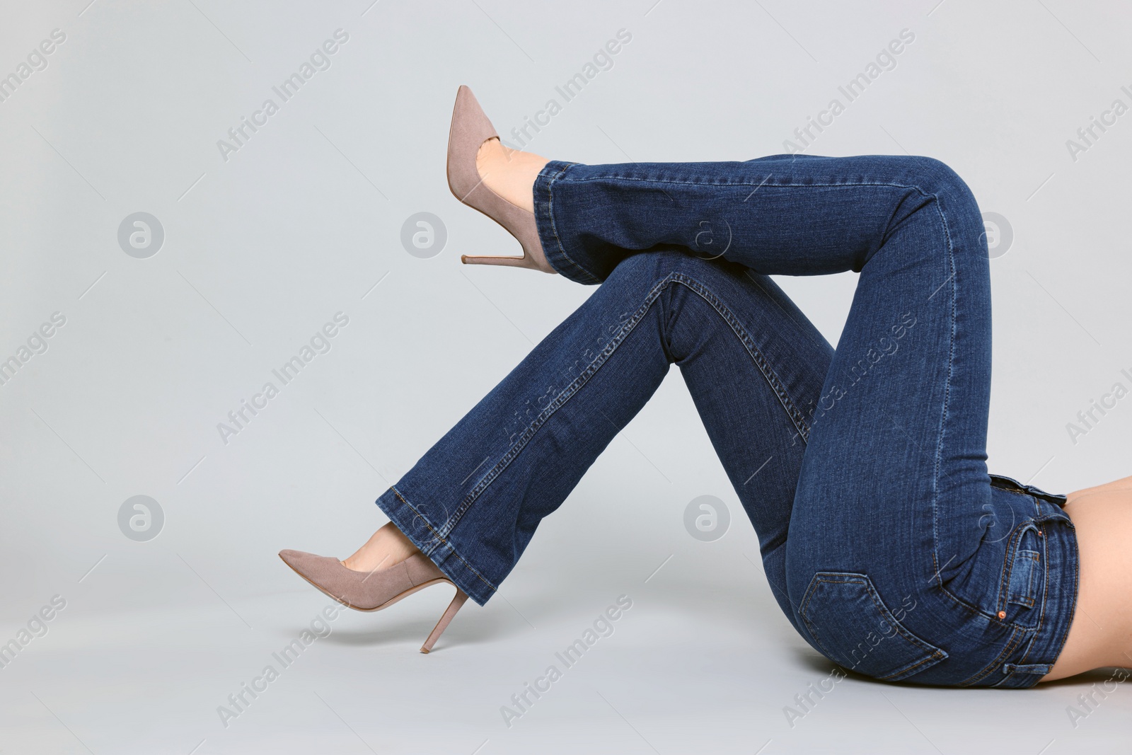 Photo of Woman in stylish jeans on grey background, closeup. Space for text