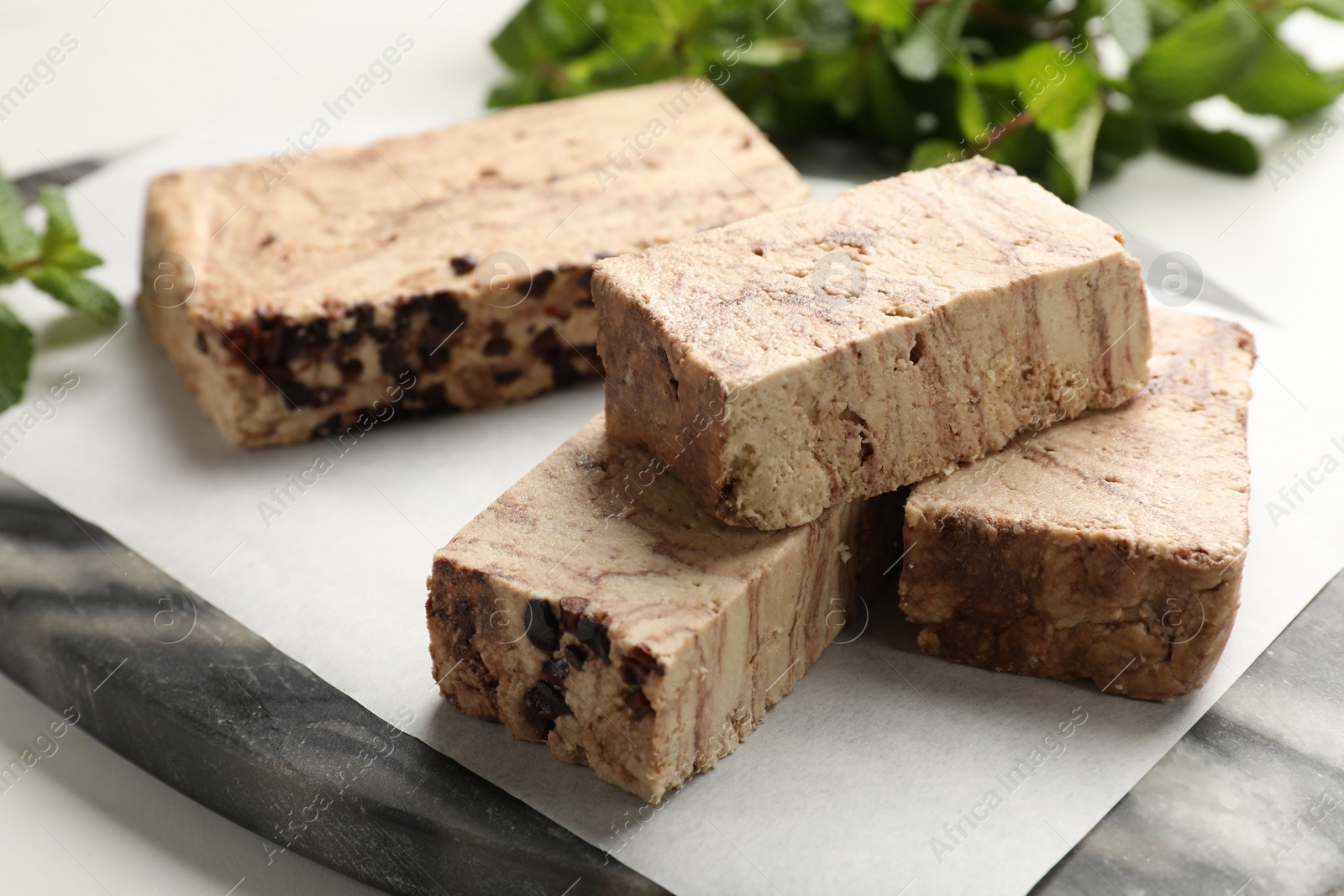 Photo of Pieces of tasty chocolate halva on table, closeup