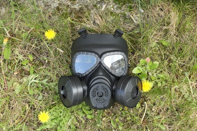 One gas mask on green grass outdoors, top view