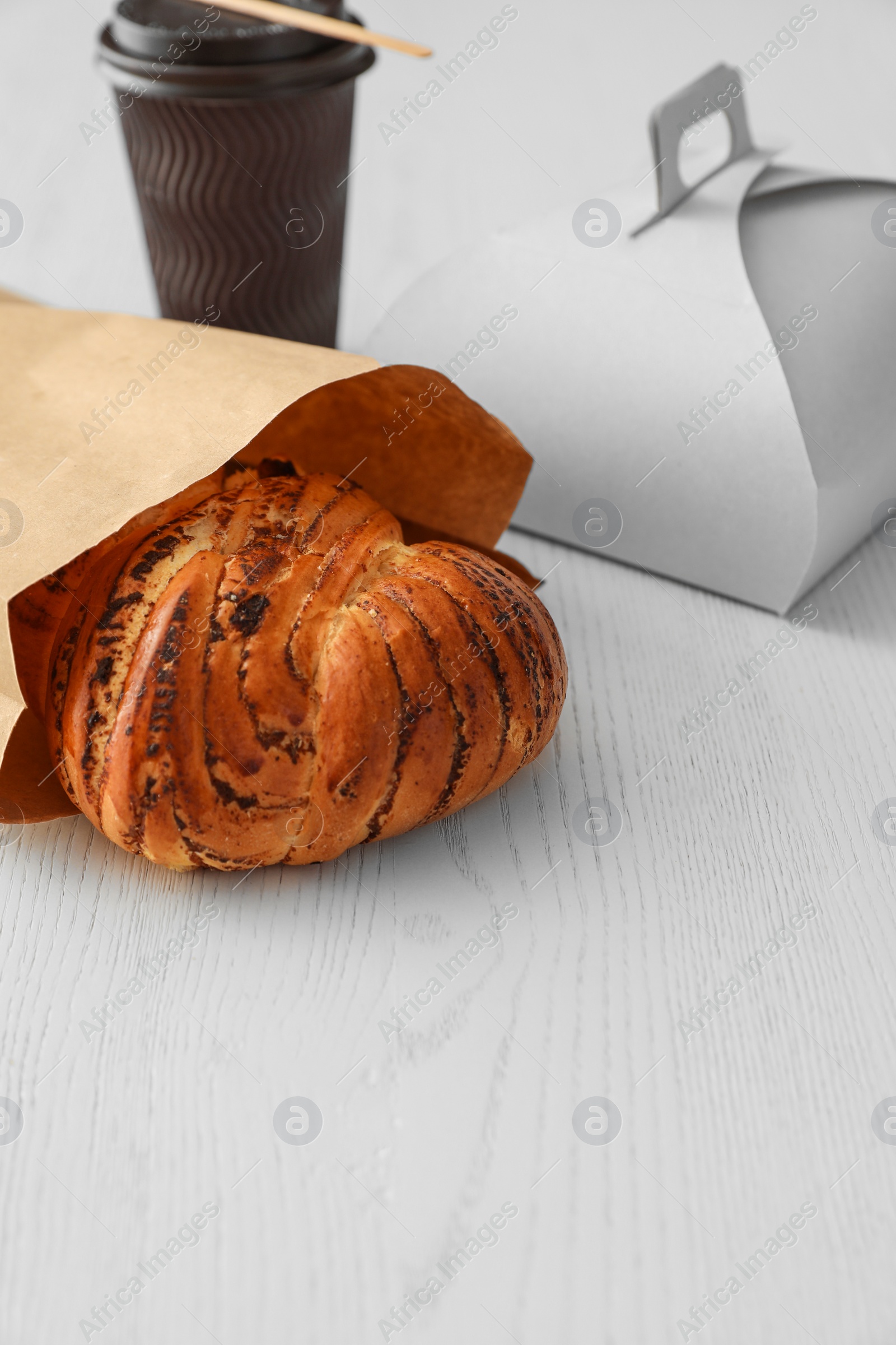 Photo of Paper bag with pastry and takeaway food on wooden table. Space for text