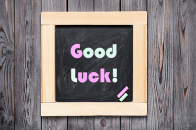 Image of Blackboard with phrase GOOD LUCK on wooden background, top view