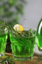 Glasses of refreshing tarragon drink with lemon on table, closeup