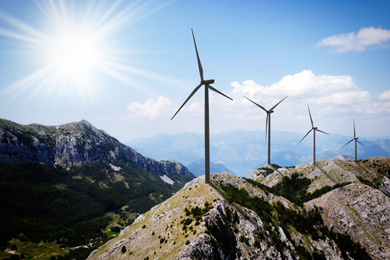 Image of Alternative energy source. Wind turbines and mountains on sunny day 