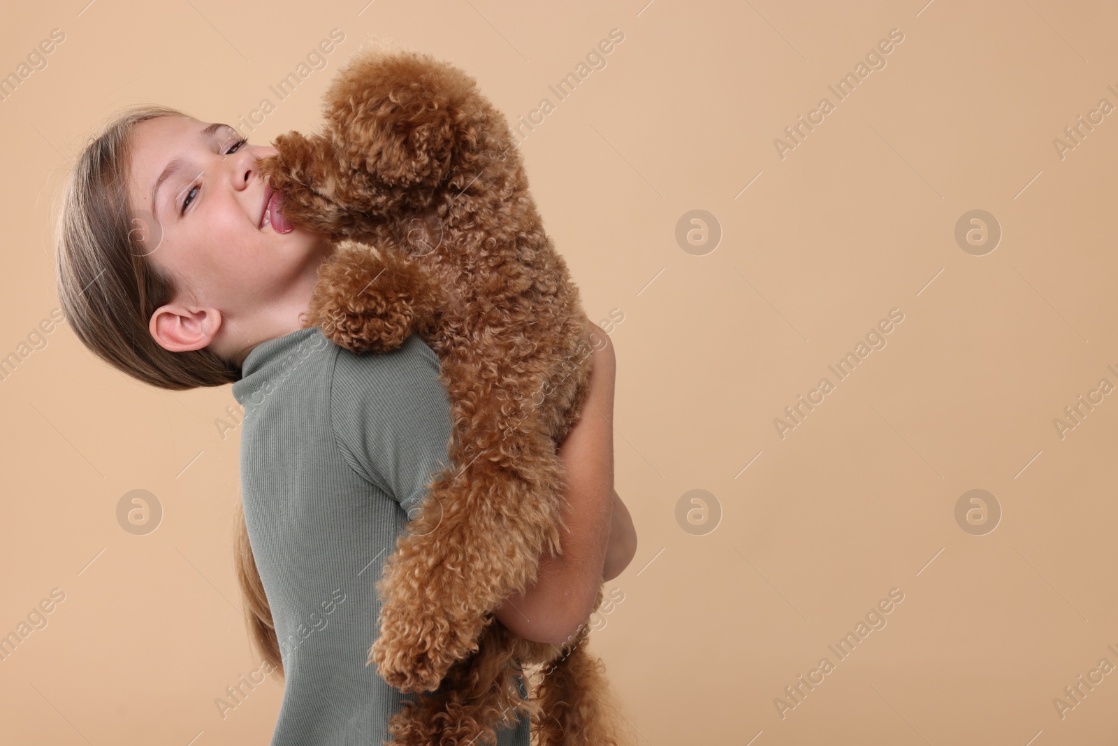 Photo of Little child with cute puppy on beige background, space for text. Lovely pet