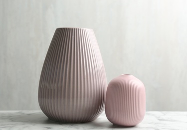 Photo of Stylish pink ceramic vases on white marble table