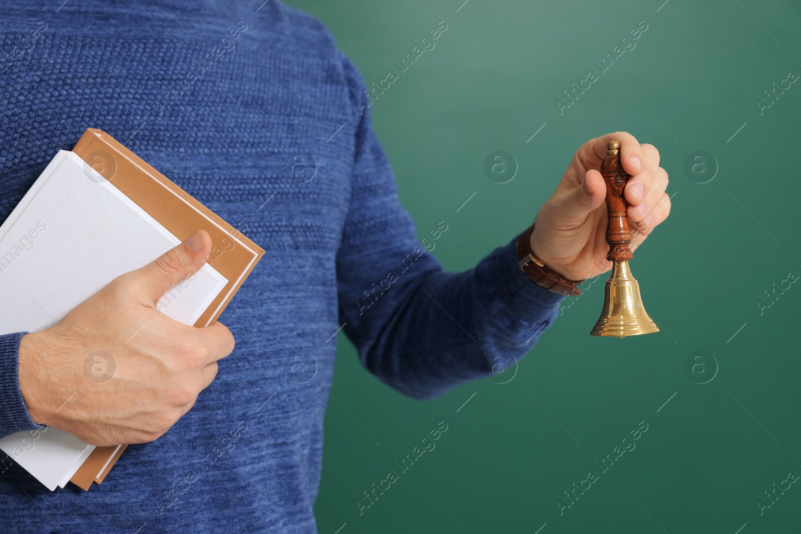 Photo of Teacher with school bell near chalkboard, closeup