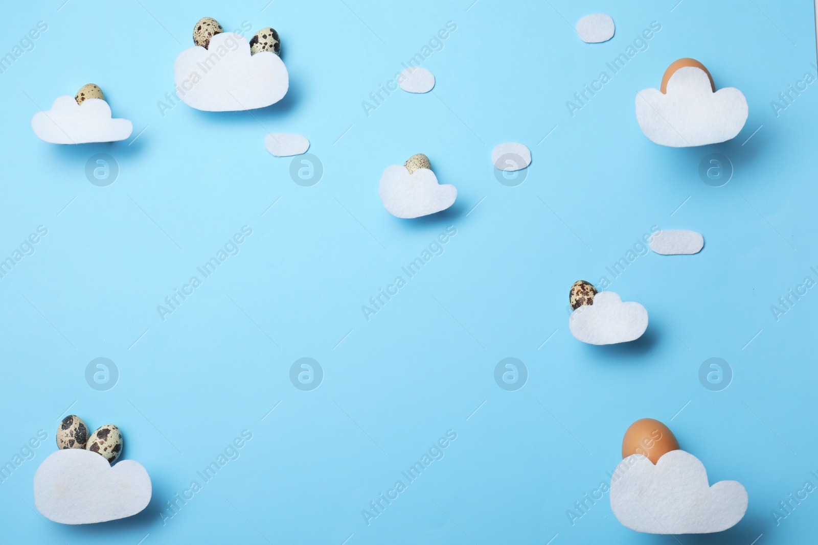 Photo of Flat lay composition of felt clouds and Easter eggs on color background, space for text