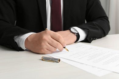 Notary signing document at wooden table, closeup