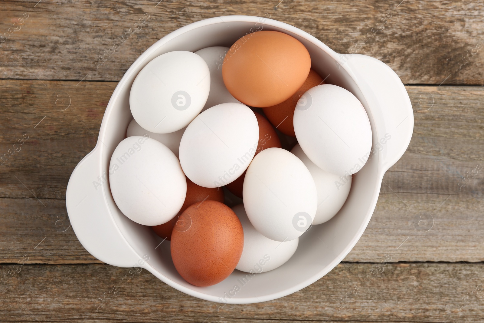 Photo of Unpeeled boiled eggs in saucepan on wooden table, top view