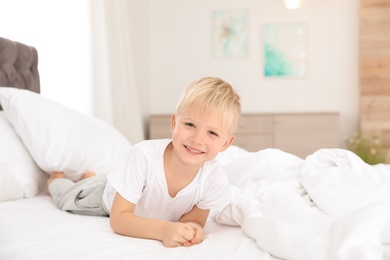 Photo of Cute little boy lying on bed at home