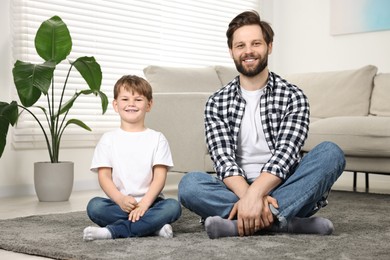 Photo of Happy dad and son sitting on carpet at home