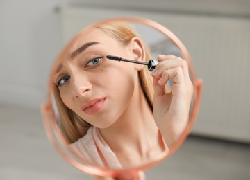 Photo of Young woman with eyelash loss problem applying mascara indoors