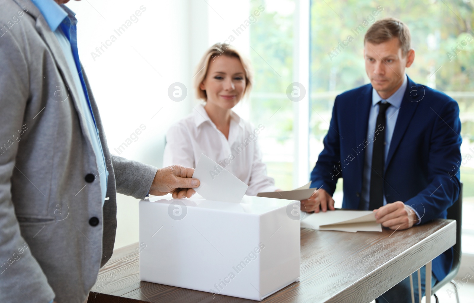 Photo of Elderly man putting ballot paper into box at polling station