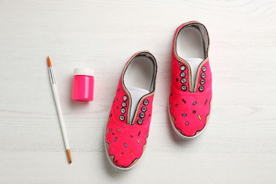 Photo of Amazing customized shoes and painting supplies on white wooden background, flat lay