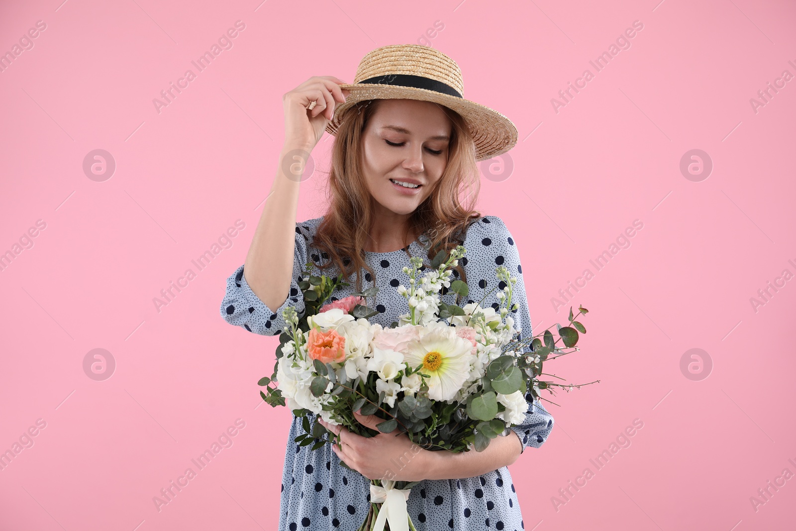 Photo of Beautiful woman in straw hat with bouquet of flowers on pink background