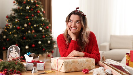 Young woman with beautifully wrapped Christmas gift at home