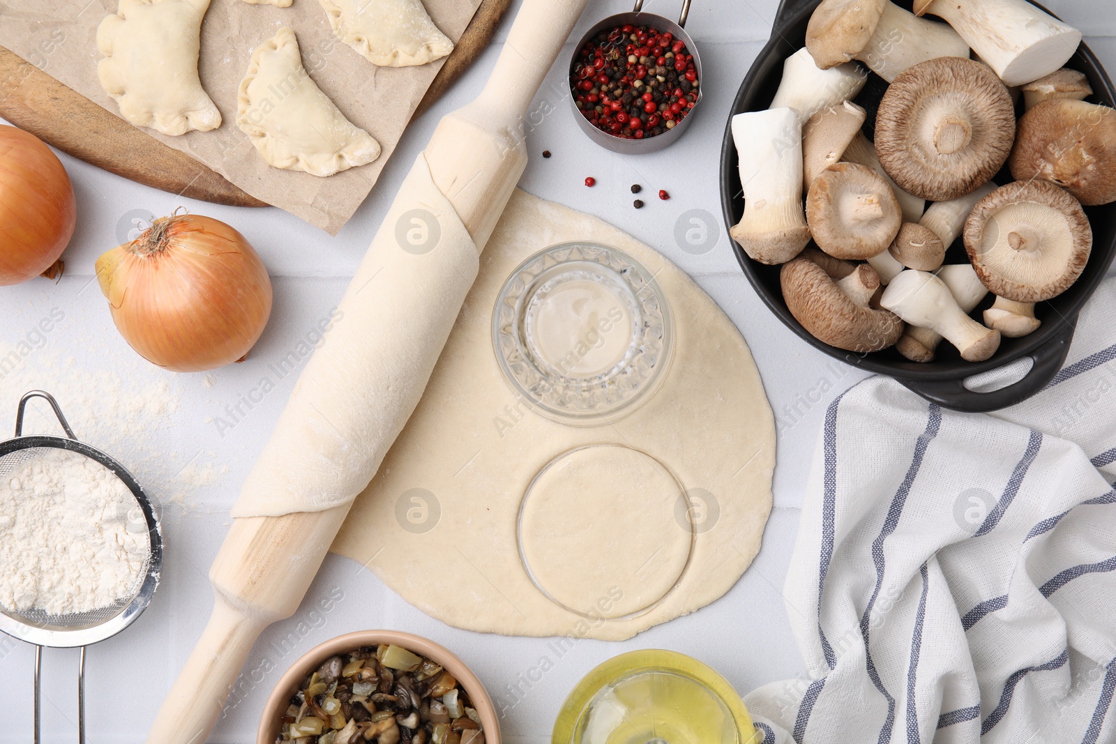 Photo of Process of making dumplings (varenyky) with mushrooms. Raw dough and ingredients on white table, flat lay