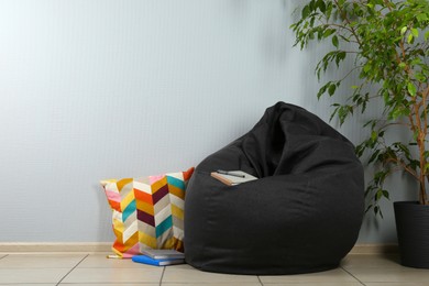 Photo of Black bean bag chair near light grey wall in room. Space for text