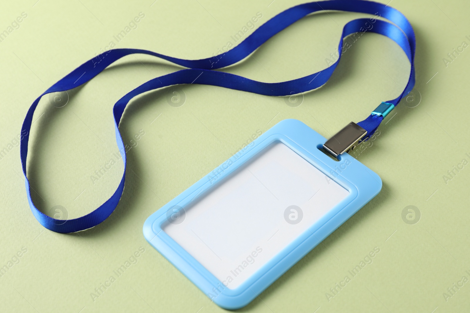 Photo of Blank light blue badge with string on green background