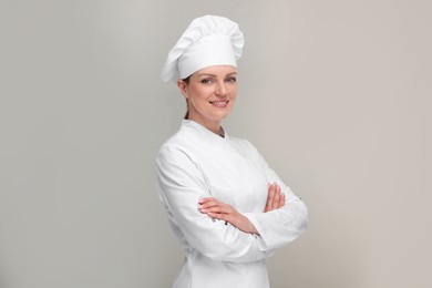 Photo of Happy chef in uniform on grey background