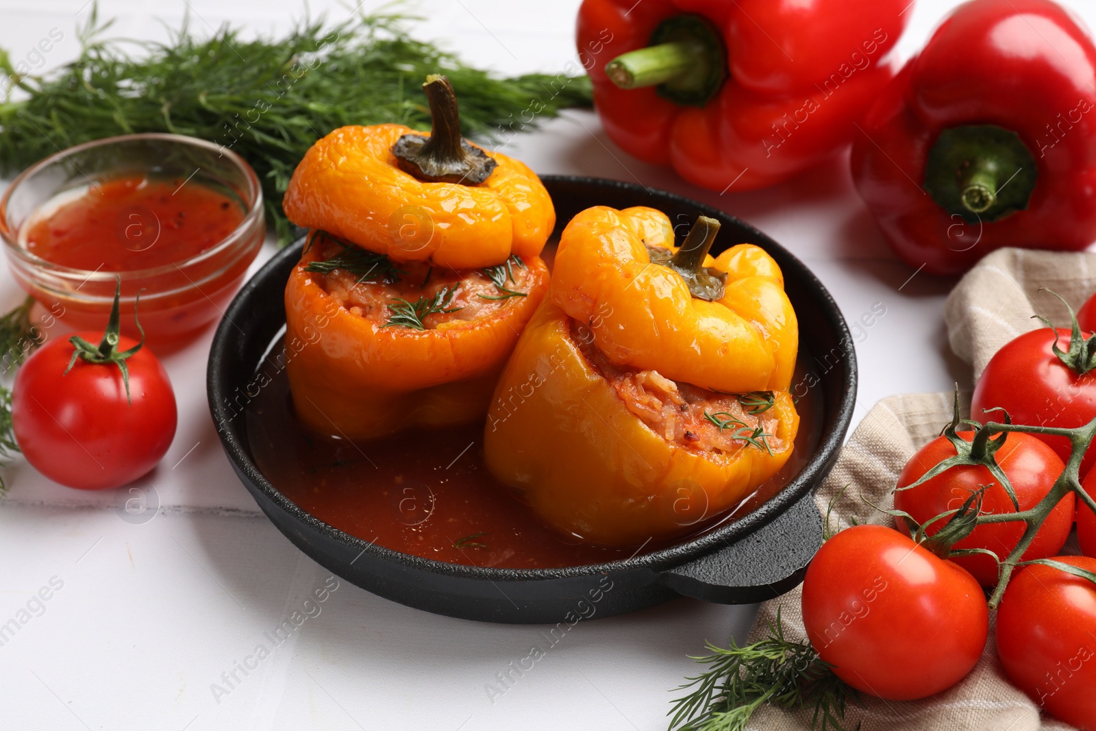 Photo of Tasty stuffed peppers and products on light tiled table, closeup