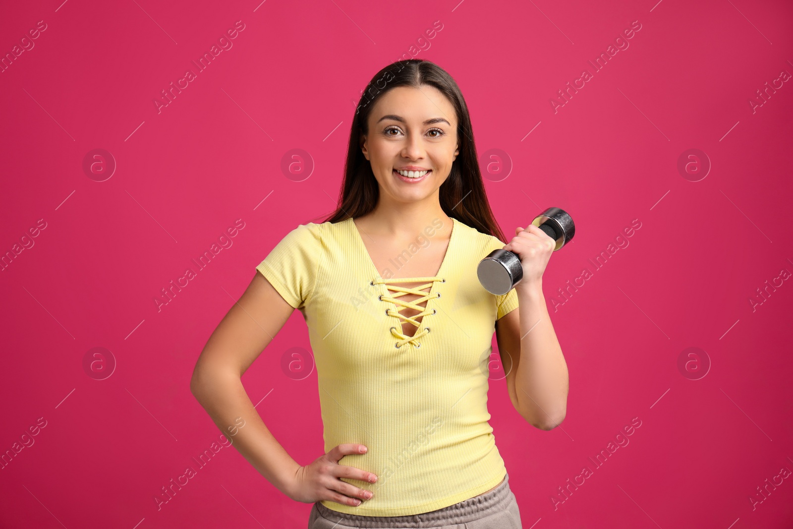 Photo of Woman with dumbbell as symbol of girl power on pink background. 8 March concept