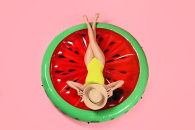 Young woman wearing stylish swimsuit on inflatable mattress against pink background, above view