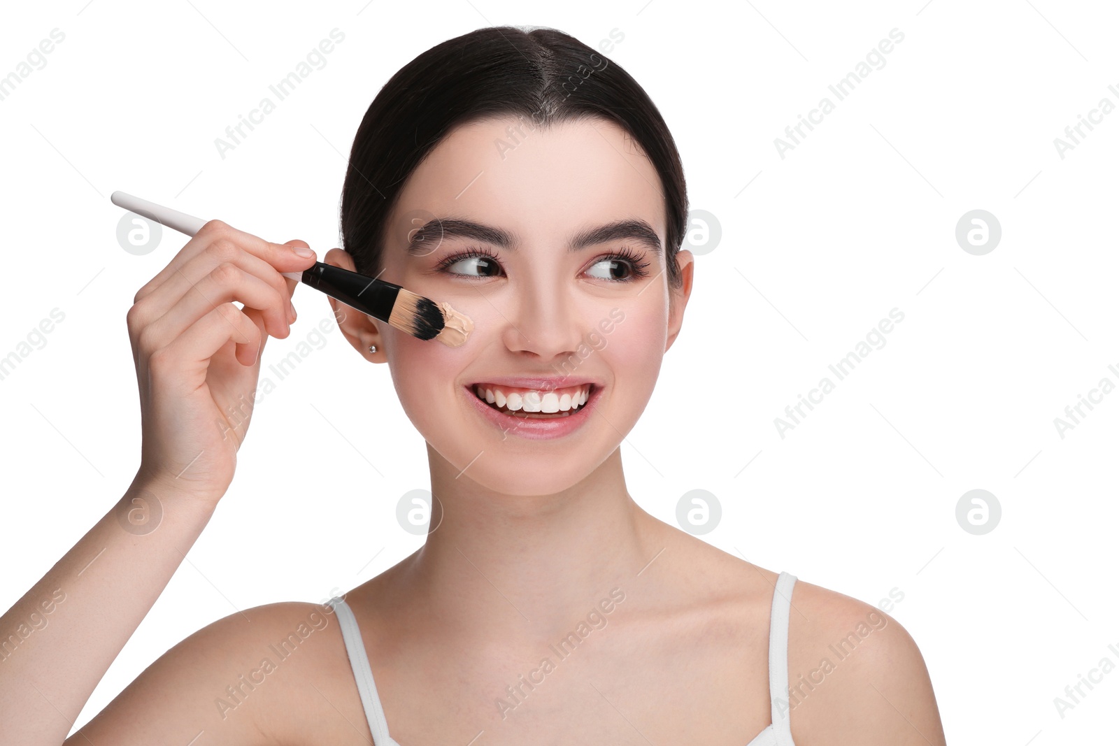 Photo of Teenage girl applying foundation on face with brush against white background