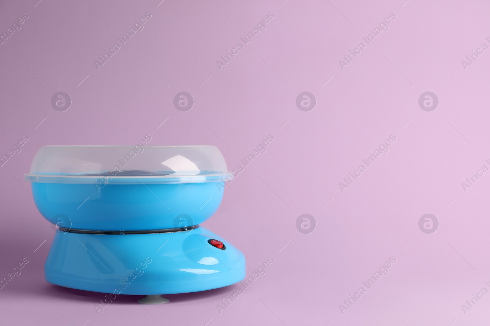 Photo of Portable candy cotton machine on violet background, space for text