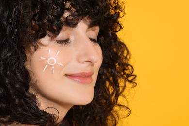 Photo of Beautiful young woman with sun protection cream on her face against orange background, closeup. Space for text