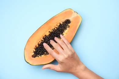 Young woman touching half of papaya on blue background, top view. Sex concept
