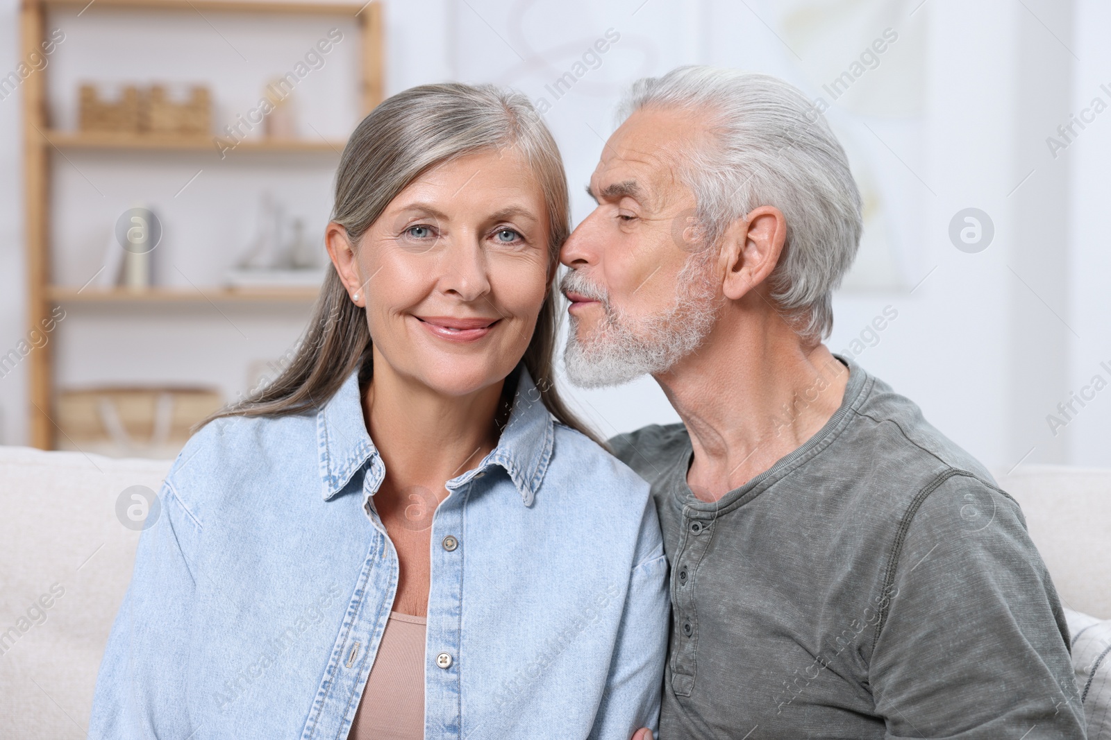 Photo of Senior man kissing his beloved woman indoors