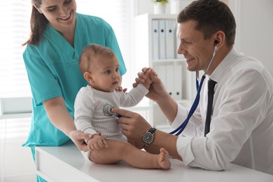 Photo of Pediatrician examining cute little baby in clinic