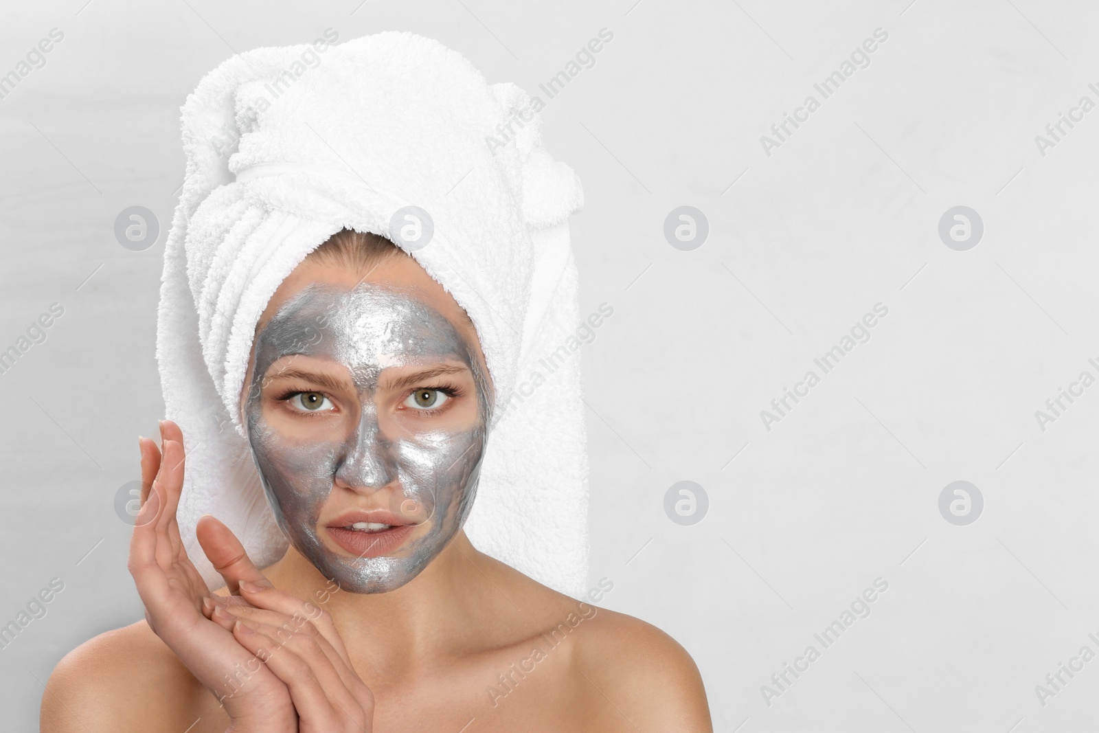 Photo of Beautiful woman with silver mask on her face against light background. Space for text