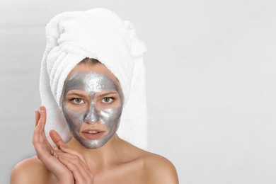 Photo of Beautiful woman with silver mask on her face against light background. Space for text