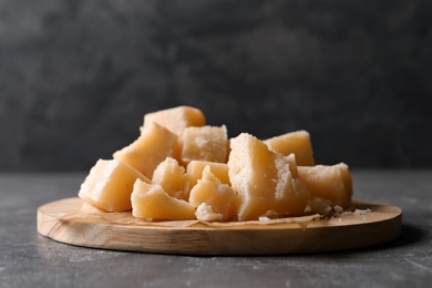 Photo of Parmesan cheese with wooden board on grey table