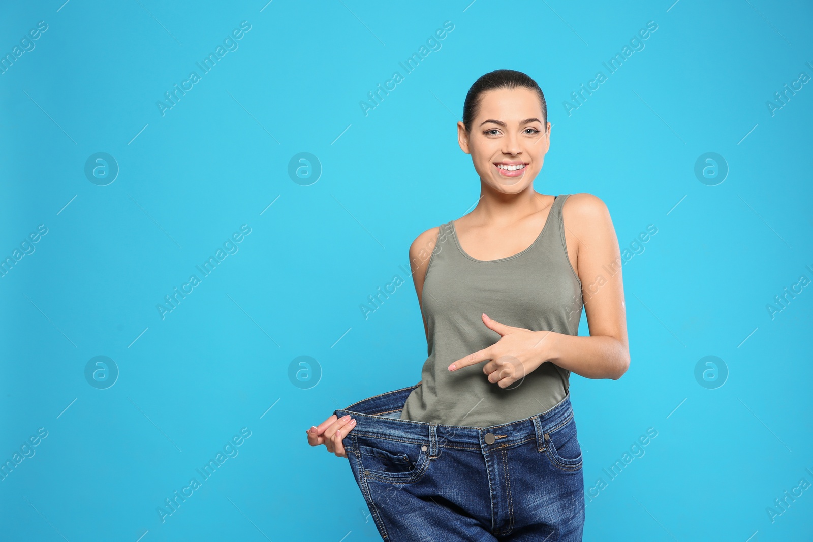 Photo of Slim woman in oversized jeans on color background, space for text. Weight loss