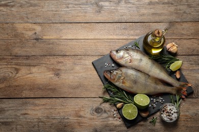 Photo of Fresh raw perches and ingredients on wooden table, flat lay with space for text. River fish