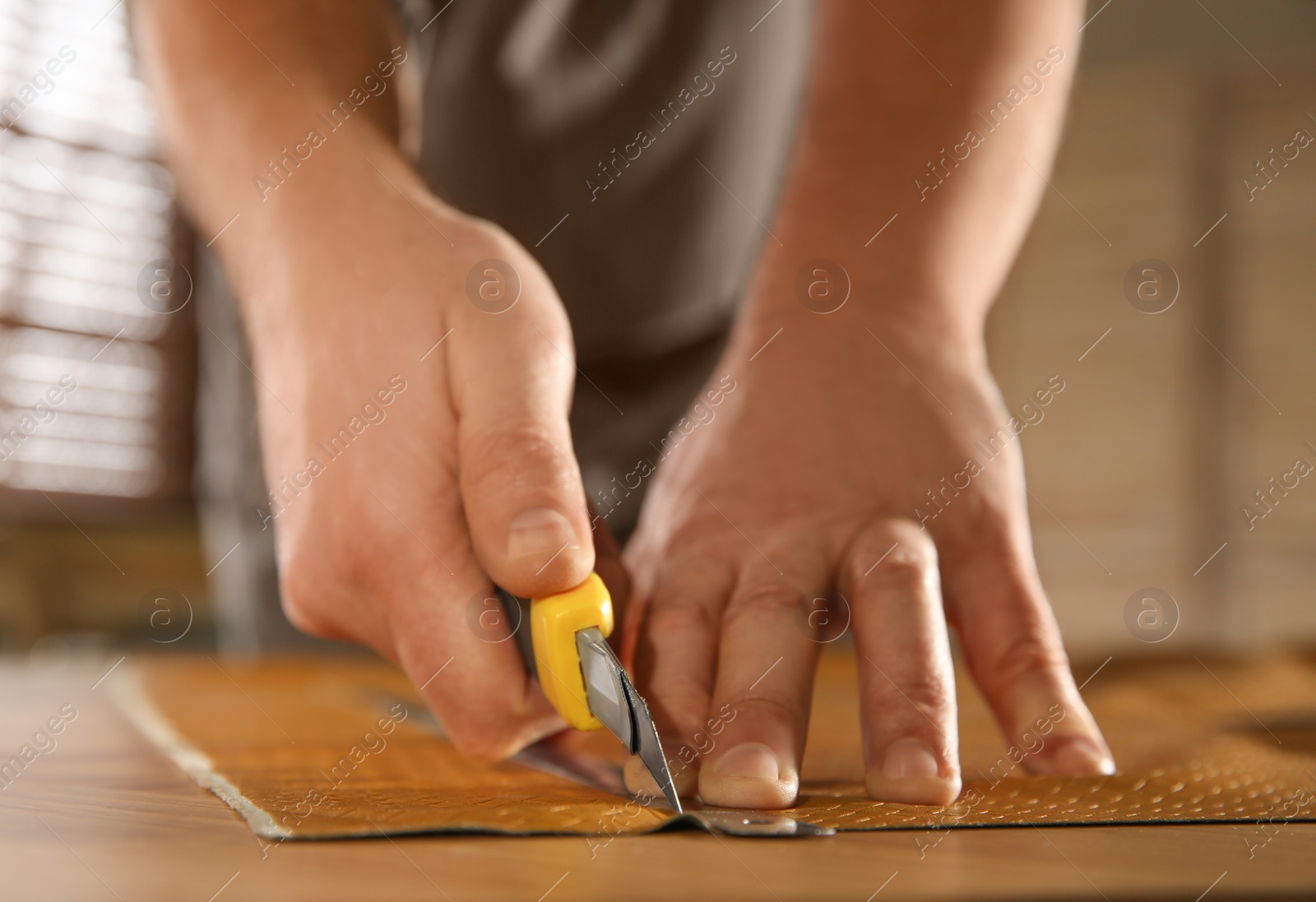Photo of Man cutting leather with knife in workshop, closeup