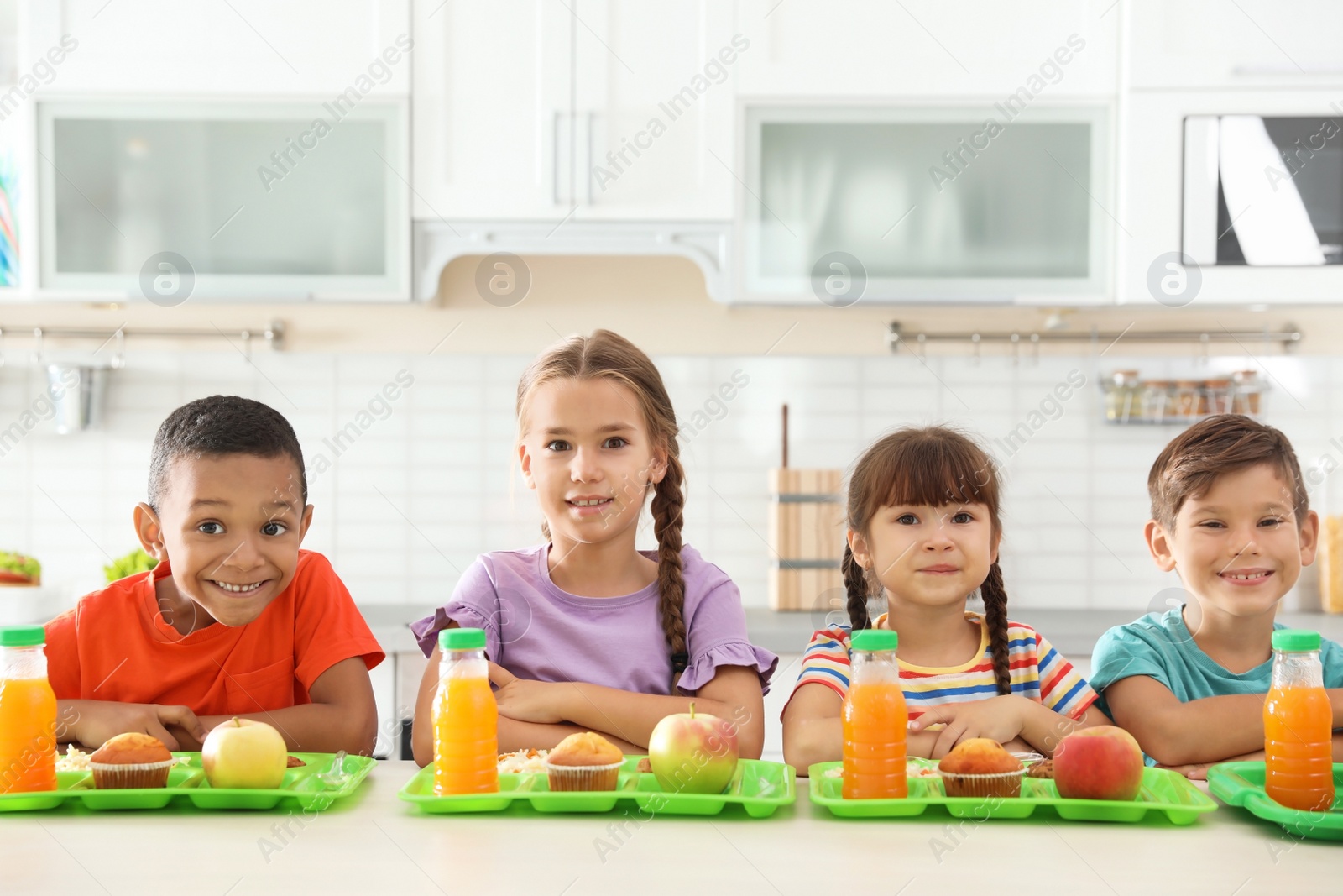 Photo of Children sitting at table and eating healthy food during break at school