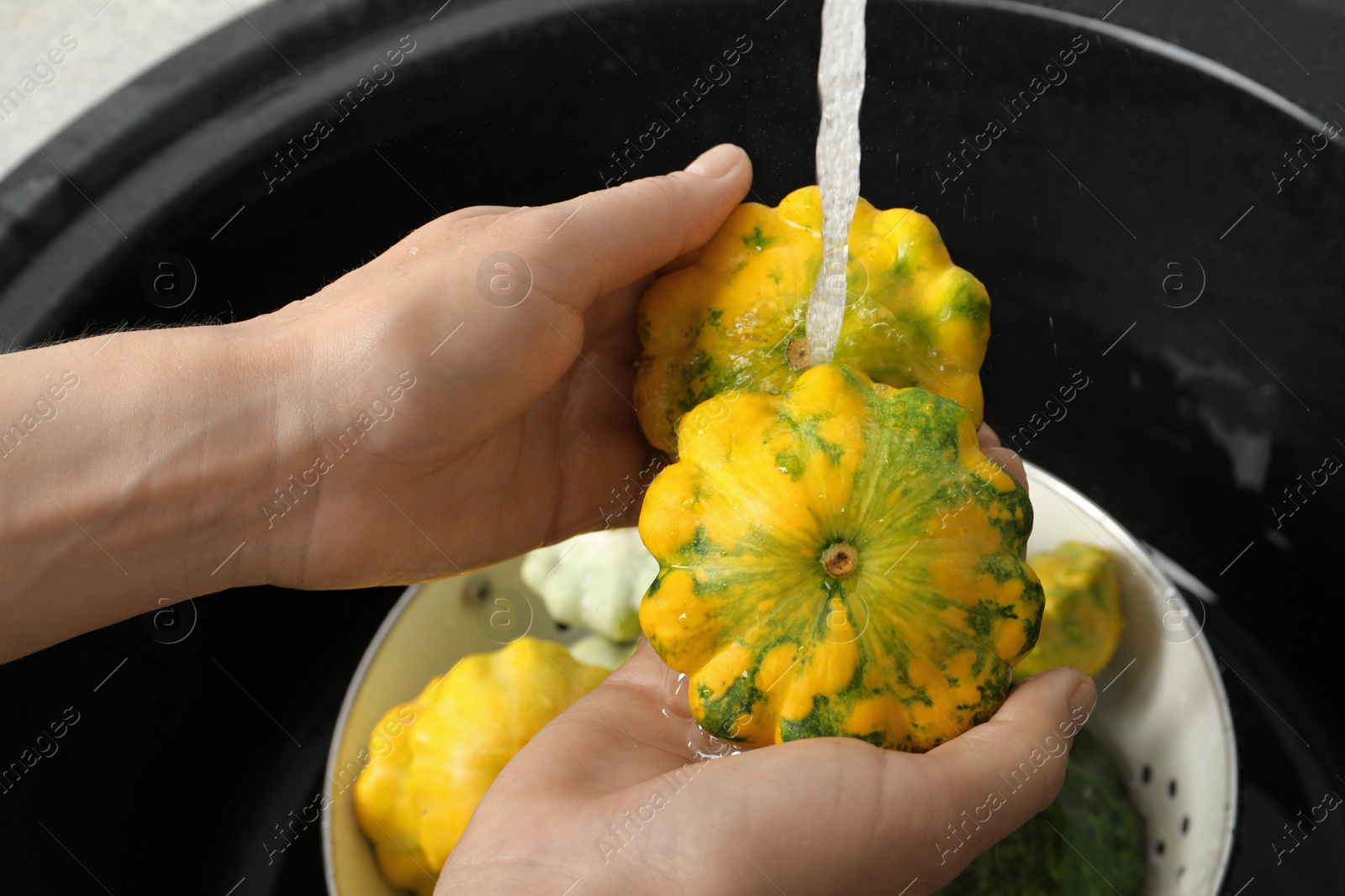 Photo of Woman washing pattypan squashes above sink, closeup