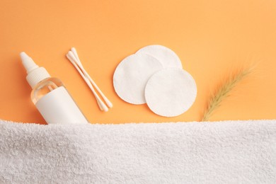 Photo of Flat lay composition with makeup remover, cotton pads and buds on pale orange background