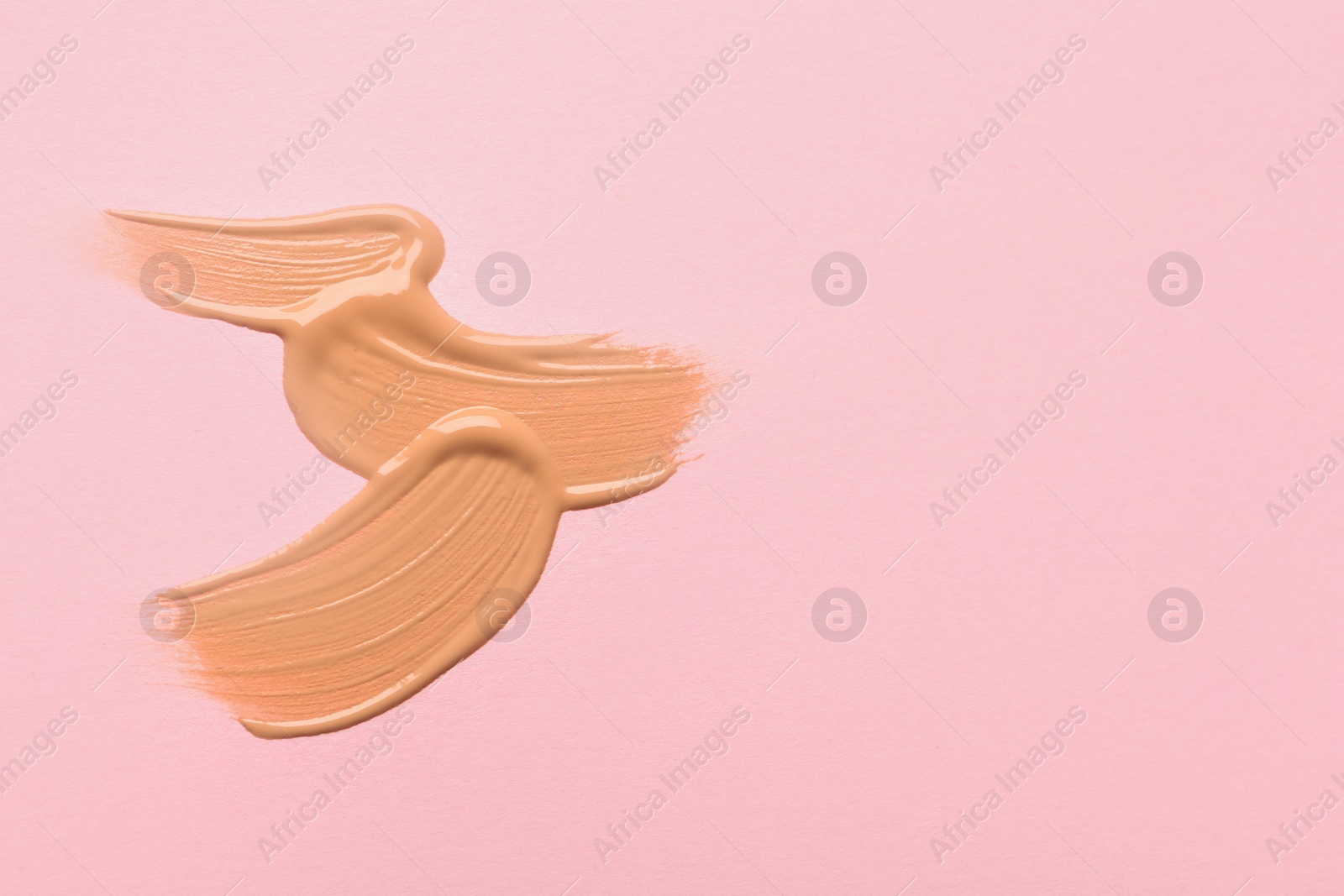 Photo of Sample of liquid skin foundation on pink background, top view. Space for text