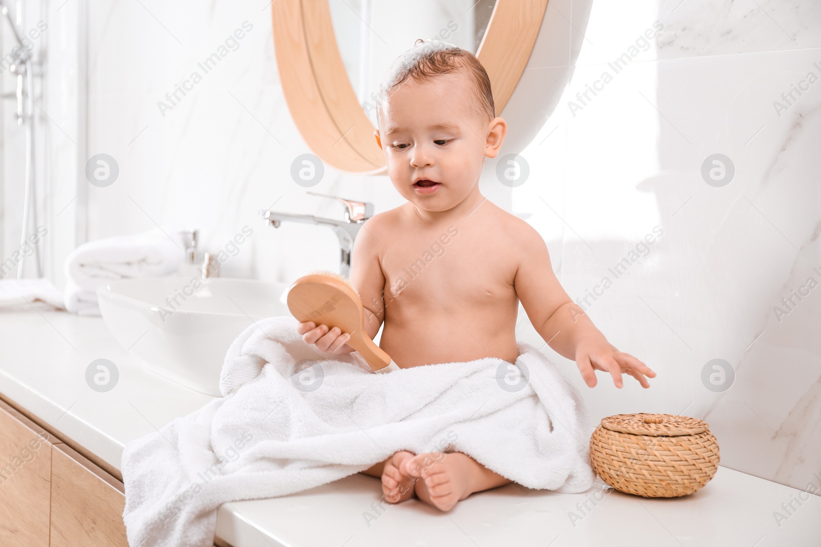 Photo of Cute little baby sitting on countertop in bathroom